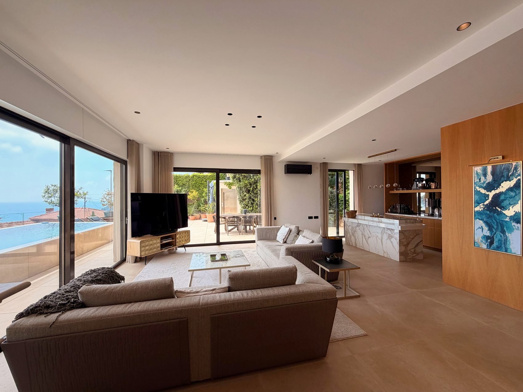 Open-plan living room with sliding glass doors onto the terrace, pool and the sea beyond